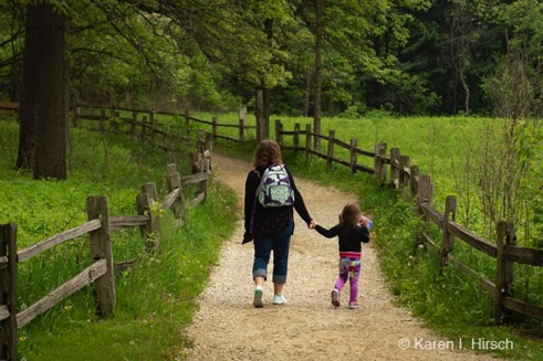 Mother holding hands with daughter, walking down path